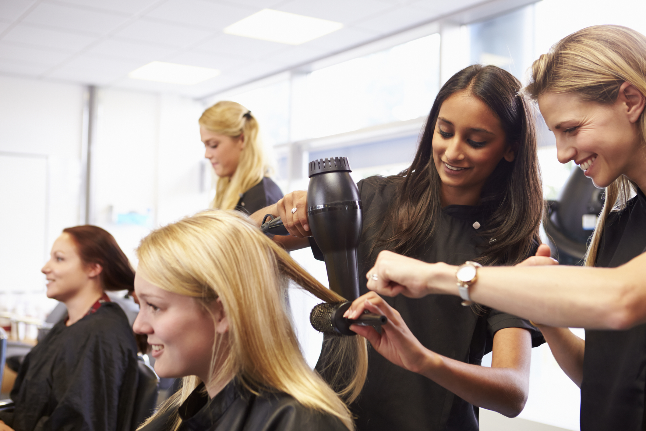 Teacher Helping Students Training To Become Hairdressers