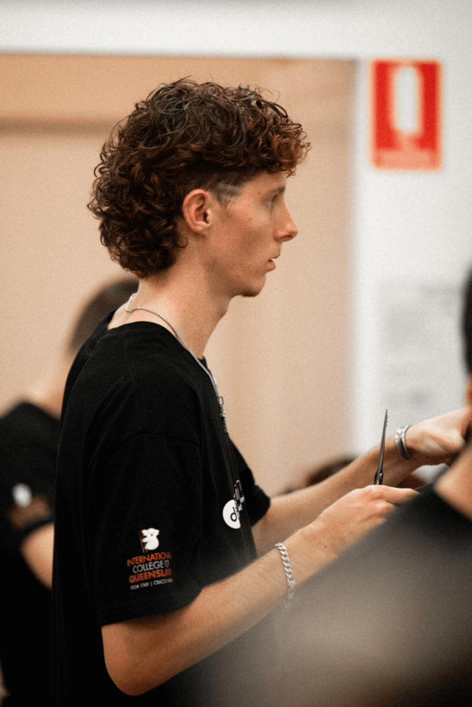 Demi barbering apprentice cutting client's hair